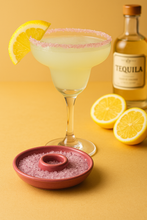 Load image into Gallery viewer, Cocktail with lemon slices, salt rim, and tequila bottle on a yellow background